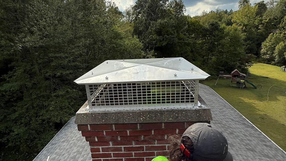 A Vonkam technician working at the top of a
           chimney on a pitched roof
